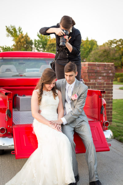 Mandy Hornbuckle shooting over bride and groom's shoulder on a red truck